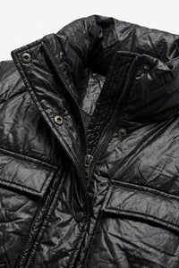 Μαύρο μπουφάν με ελαφρώς γυαλιστερή υφή, όρθιο γιακά και ζώνη στη μέση, φορεμένο από μοντέλο.