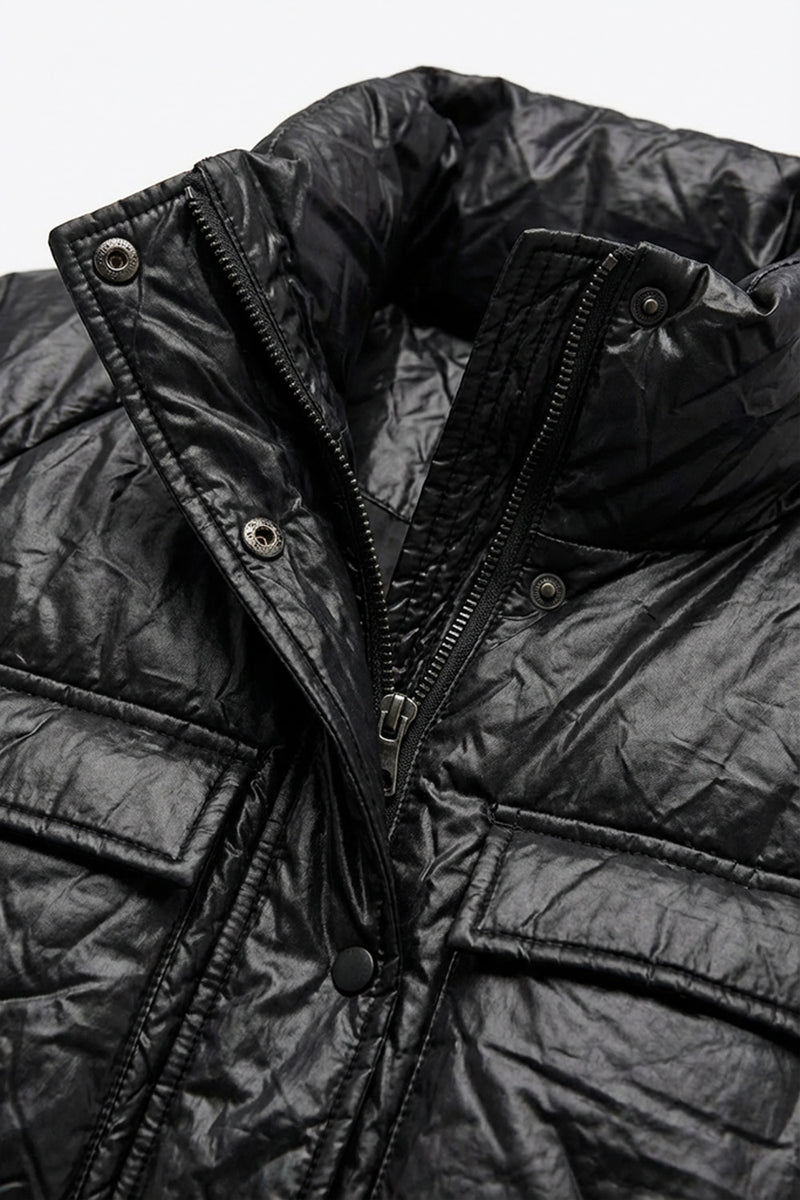 Μαύρο μπουφάν με ελαφρώς γυαλιστερή υφή, όρθιο γιακά και ζώνη στη μέση, φορεμένο από μοντέλο.