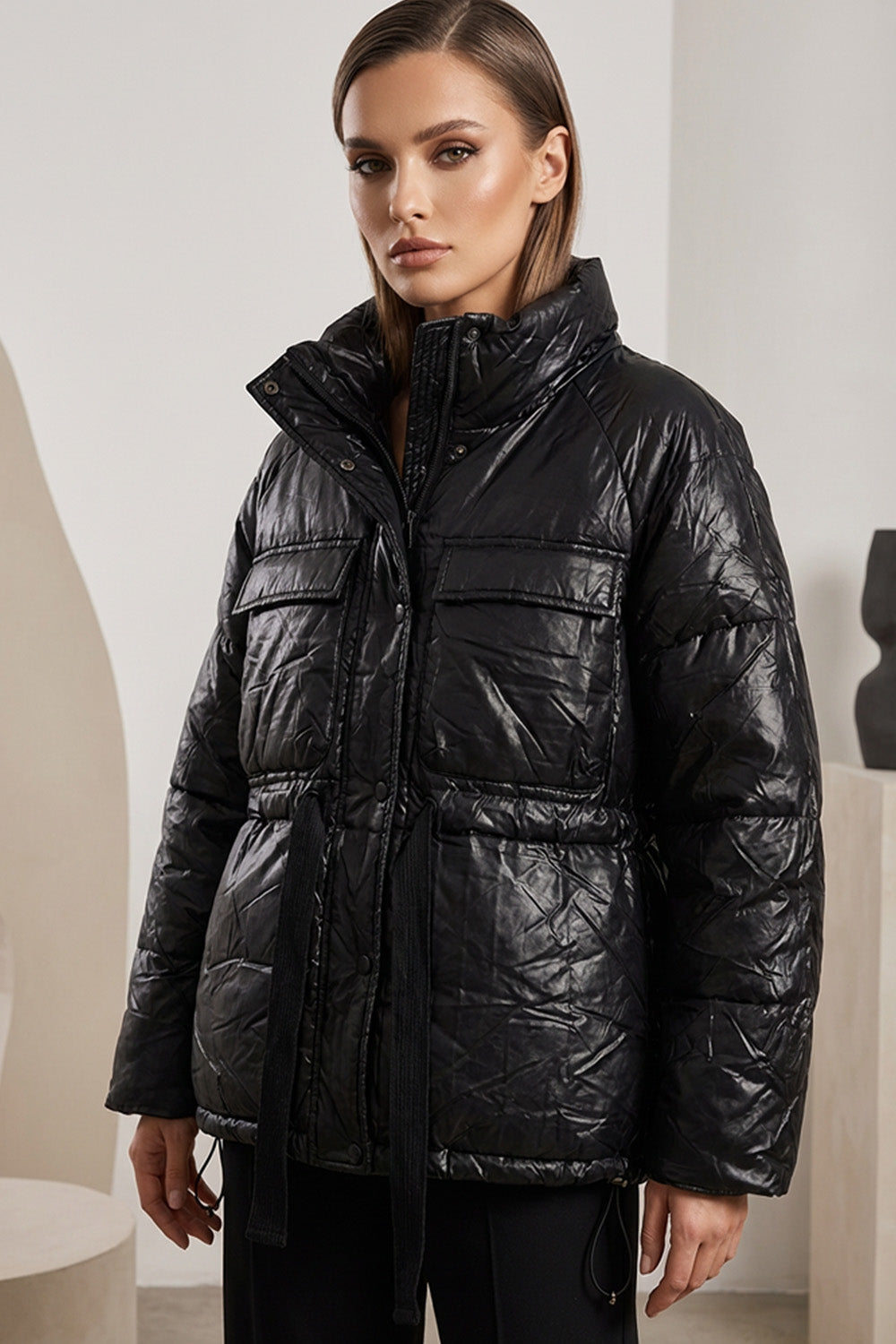 Μαύρο μπουφάν με ελαφρώς γυαλιστερή υφή, όρθιο γιακά και ζώνη στη μέση, φορεμένο από μοντέλο.