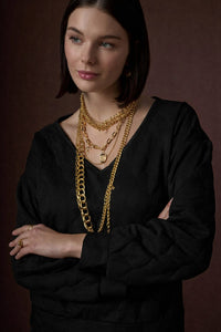 Μαύρη καπιτονέ μπλούζα γυναικεία με χρυσό κέντημα στην πλάτη, φωτογραφημένη σε studio με μοντέλο