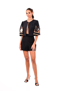 Μαύρο crop σακάκι με floral λεπτομέρειες στα μανίκια, φορεμένο από μοντέλο σε total black σύνολο.