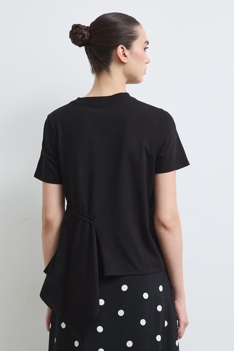 Γυναικείο μαύρο T-shirt με πλαϊνή σούρα, κορδόνι στη μέση και ασύμμετρο τελείωμα, συνδυασμένο με πουά φούστα.