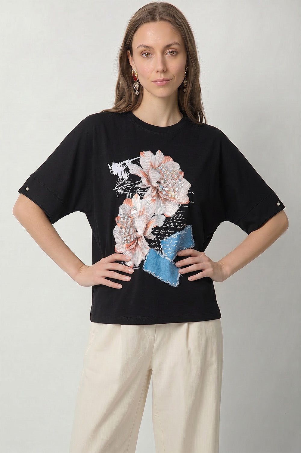 Μαύρο γυναικείο t-shirt με τρισδιάστατα λουλούδια, στρας και denim-look διακοσμητικές λεπτομέρειες.