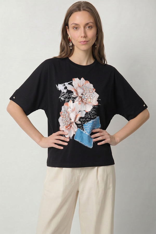 Μαύρο γυναικείο t-shirt με τρισδιάστατα λουλούδια, στρας και denim-look διακοσμητικές λεπτομέρειες.