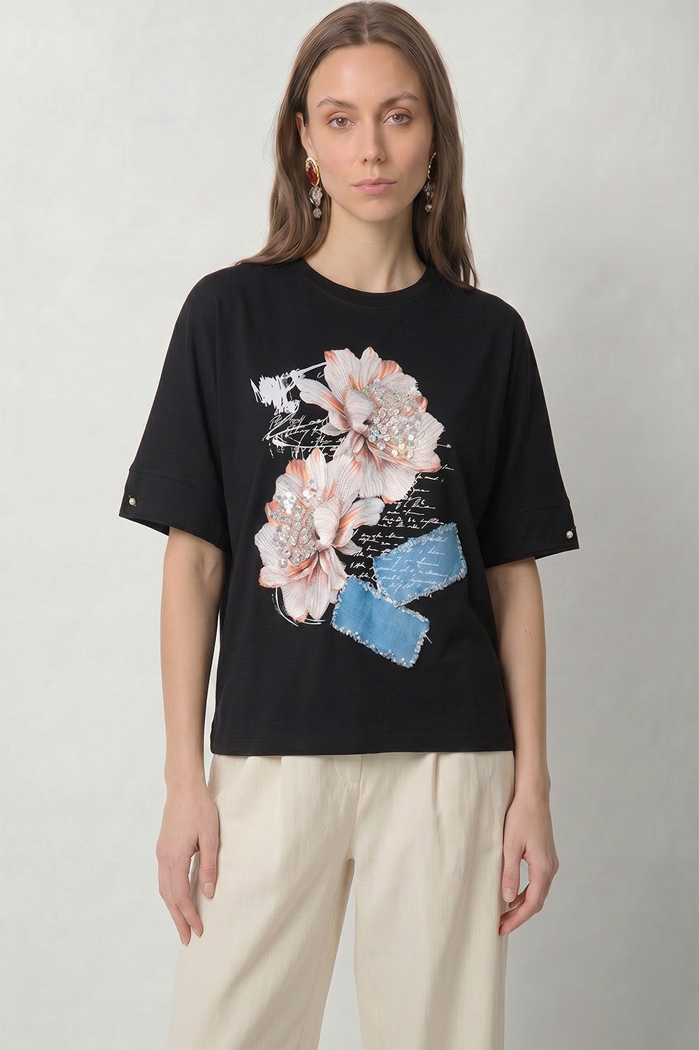 Μαύρο γυναικείο t-shirt με τρισδιάστατα λουλούδια, στρας και denim-look διακοσμητικές λεπτομέρειες.