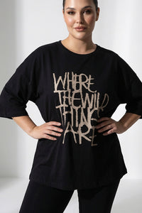 Μαύρο γυναικείο T-shirt με τύπωμα “Where the Wild Things Are” σε άνετη γραμμή, φορεμένο από μοντέλο.