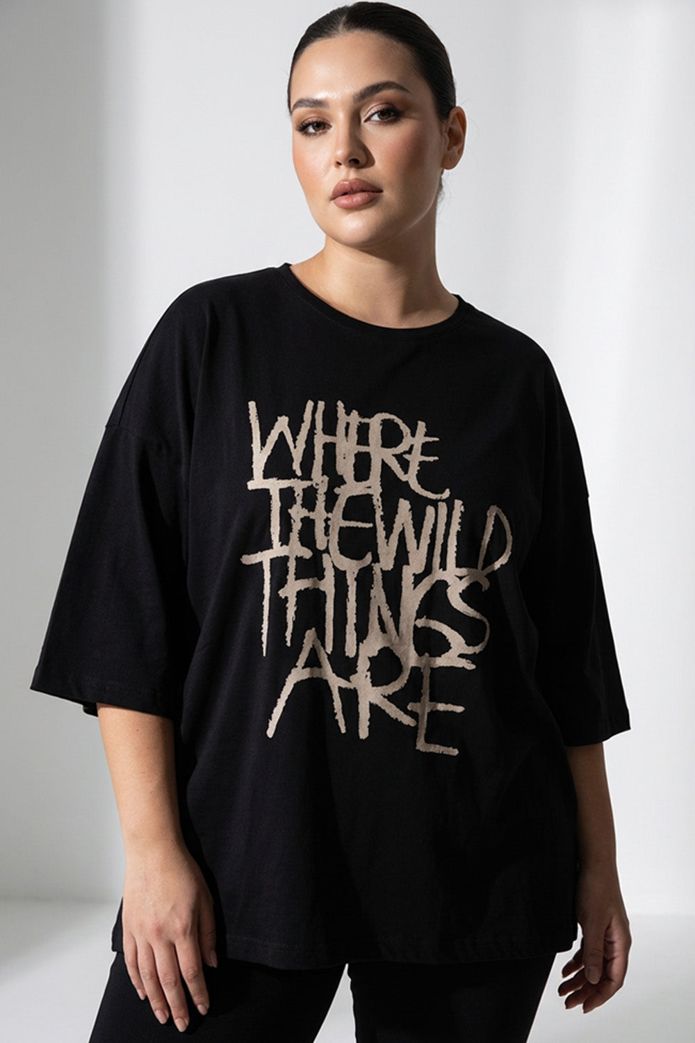Μαύρο γυναικείο T-shirt με τύπωμα “Where the Wild Things Are” σε άνετη γραμμή, φορεμένο από μοντέλο.