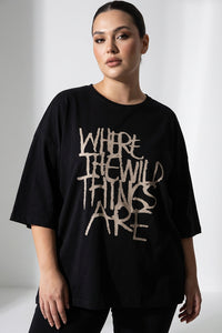 Μαύρο γυναικείο T-shirt με τύπωμα “Where the Wild Things Are” σε άνετη γραμμή, φορεμένο από μοντέλο.