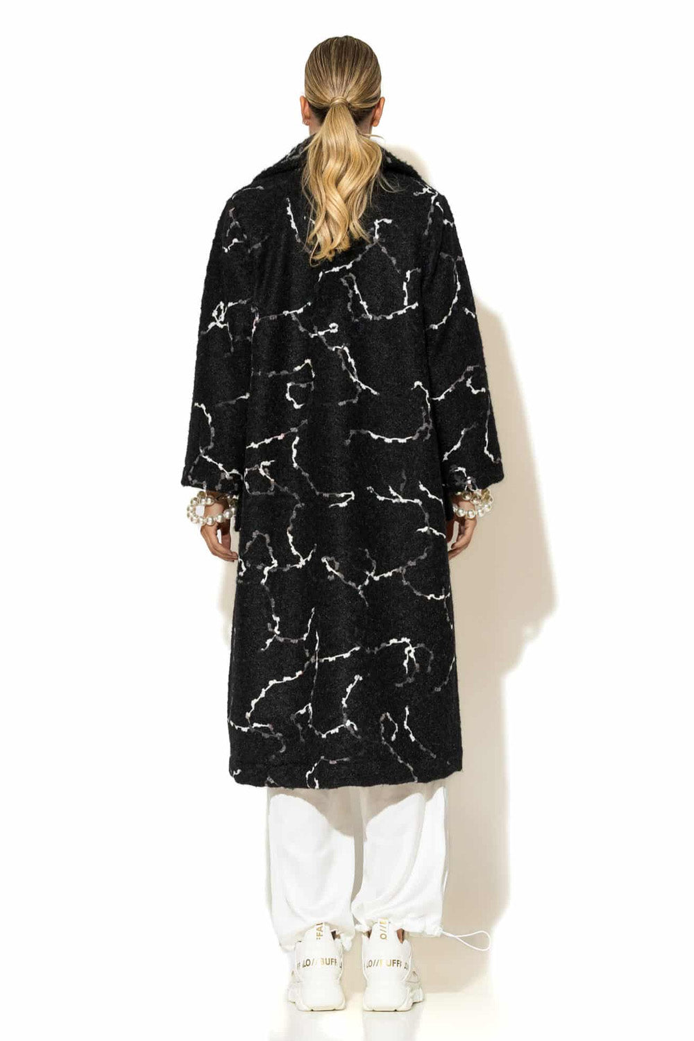 Μονόπετο παλτό ζακάρ μπουκλέ σε μαύρο χρώμα με λευκό μοτίβο, μακριά γραμμή και άνετη εφαρμογή, φορεμένο σε total white σύνολο.