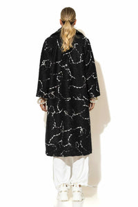 Μονόπετο παλτό ζακάρ μπουκλέ σε μαύρο χρώμα με λευκό μοτίβο, μακριά γραμμή και άνετη εφαρμογή, φορεμένο σε total white σύνολο.