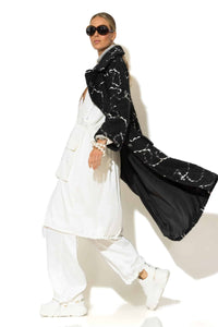 Μονόπετο παλτό ζακάρ μπουκλέ σε μαύρο χρώμα με λευκό μοτίβο, μακριά γραμμή και άνετη εφαρμογή, φορεμένο σε total white σύνολο.