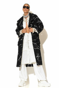 Μονόπετο παλτό ζακάρ μπουκλέ σε μαύρο χρώμα με λευκό μοτίβο, μακριά γραμμή και άνετη εφαρμογή, φορεμένο σε total white σύνολο.