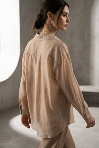 Μπεζ διάφανο πουκάμισο με κουμπιά και μακριά μανίκια, φορεμένο σε μοντέλο σε minimal studio σκηνικό.