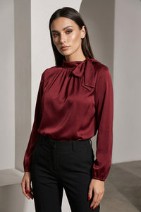 Μπορντό μπλούζα με δέσιμο στο λαιμό και μακρύ μανίκι, κομψή γραμμή, φορεμένη από μοντέλο σε minimal studio φόντο