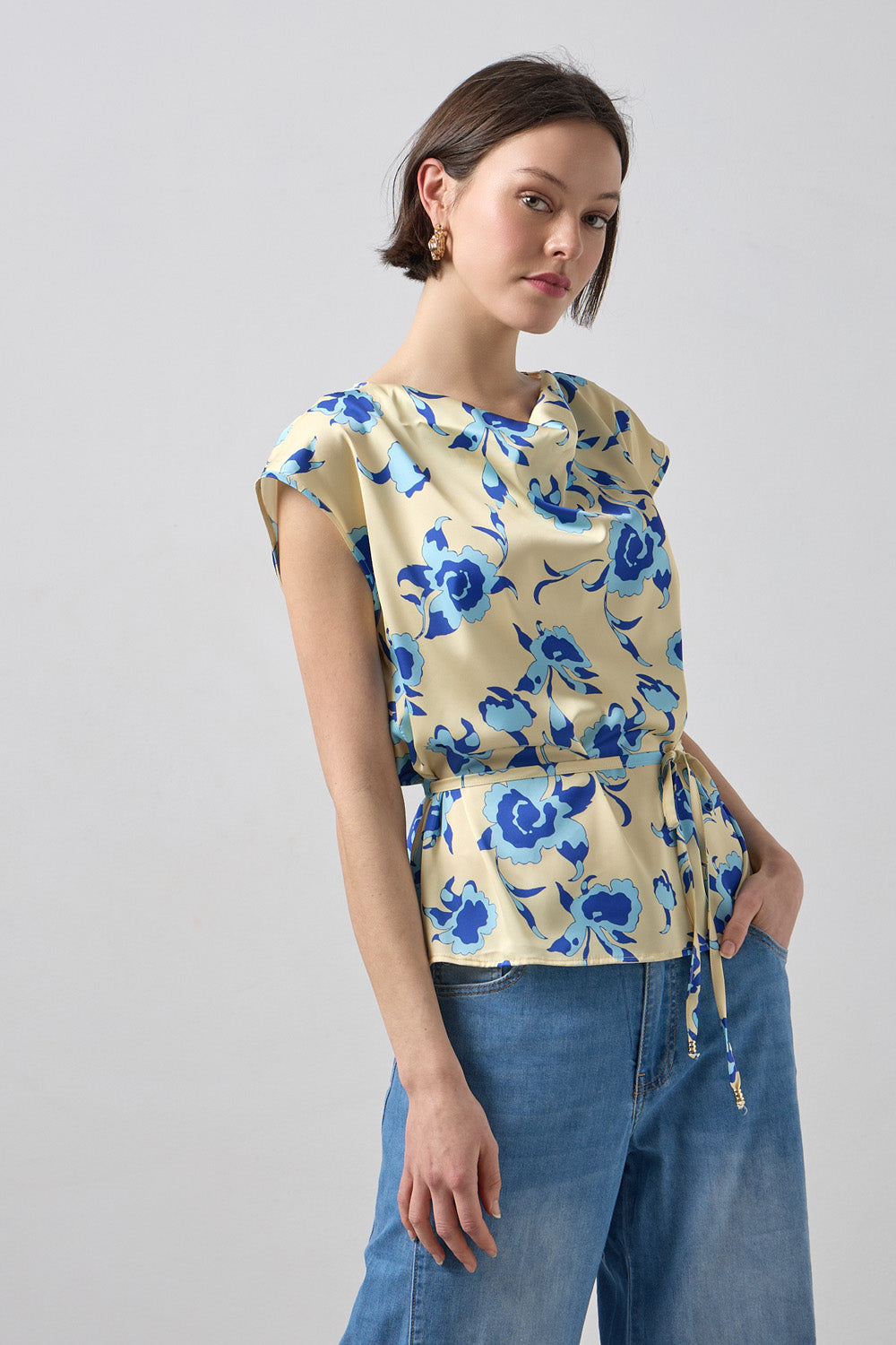 Γυναικεία μπεζ μπλούζα με μπλε φλοράλ σχέδιο, ντραπέ λαιμόκοψη και ζωνάκι στη μέση