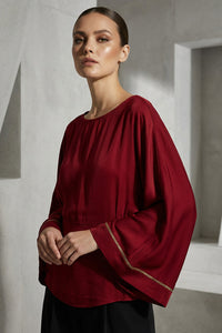Κόκκινη μπλούζα iRous με φαρδιά μανίκια και χρυσοκεντημένο σχέδιο στην πλάτη, φωτογράφιση στούντιο.