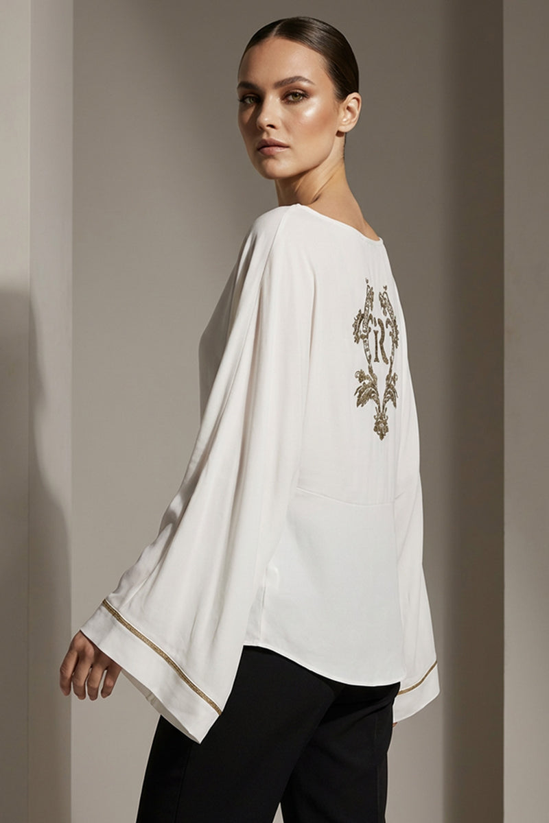 Λευκή μπλούζα iRous με φαρδιά μανίκια και χρυσοκεντημένο σχέδιο στην πλάτη, φωτογράφιση στούντιο.
