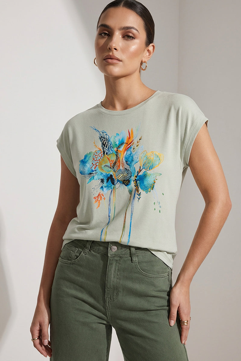 Γυναικεία φυστικί μπλούζα με καλλιτεχνικό τύπωμα σε μπλε και ώχρα αποχρώσεις, φορεμένη με χακί παντελόνι.