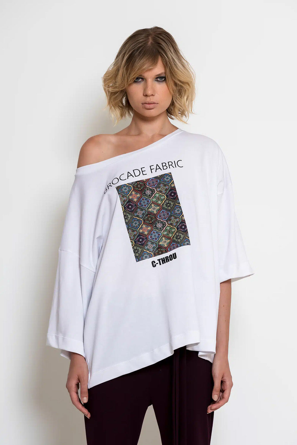 Λευκό oversized T-shirt C-THROU με φαρδιά λαιμόκοψη, ασύμμετρα μανίκια και πολύχρωμη στάμπα.