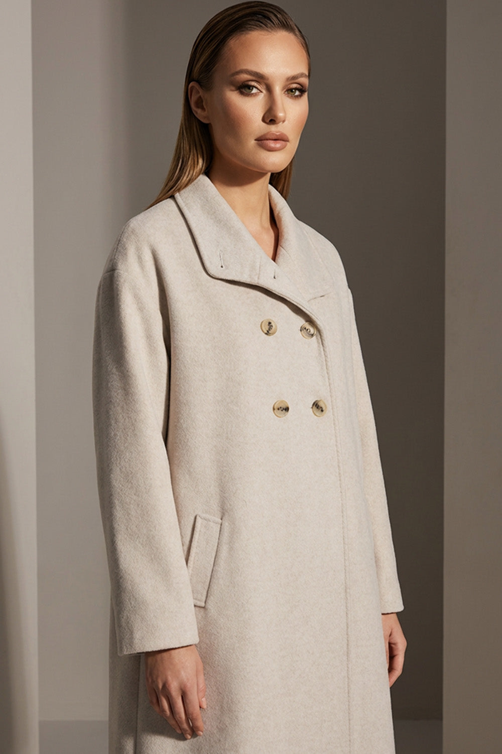 Εκρού παλτό με διπλό κούμπωμα και ίσια γραμμή, φορεμένο από μοντέλο.