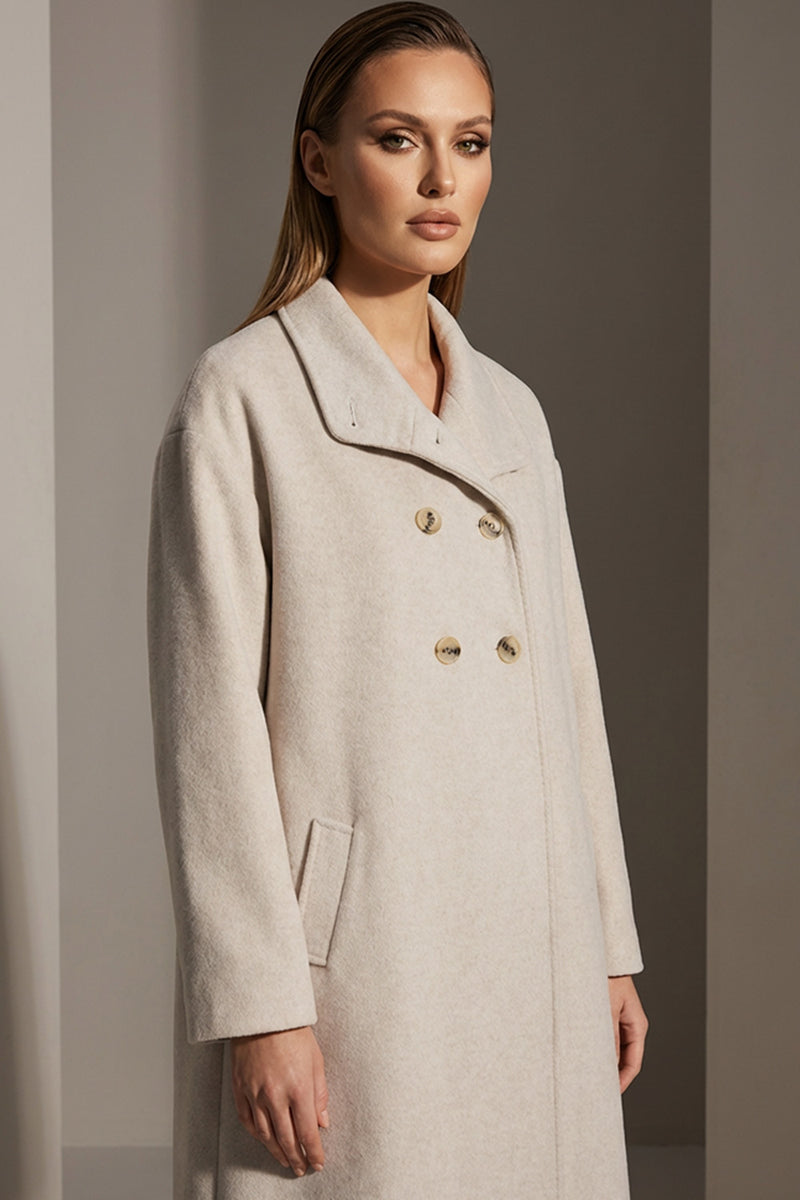 Εκρού παλτό με διπλό κούμπωμα και ίσια γραμμή, φορεμένο από μοντέλο.