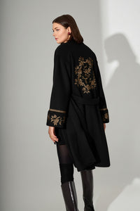 Μαύρο παλτό με χρυσές κεντημένες λεπτομέρειες, άνετη γραμμή, ζώνη στη μέση και κομψά μανίκια.