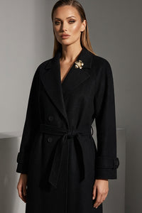 Μαύρο παλτό με ζώνη στη μέση και διακοσμητική καρφίτσα, φορεμένο από μοντέλο.