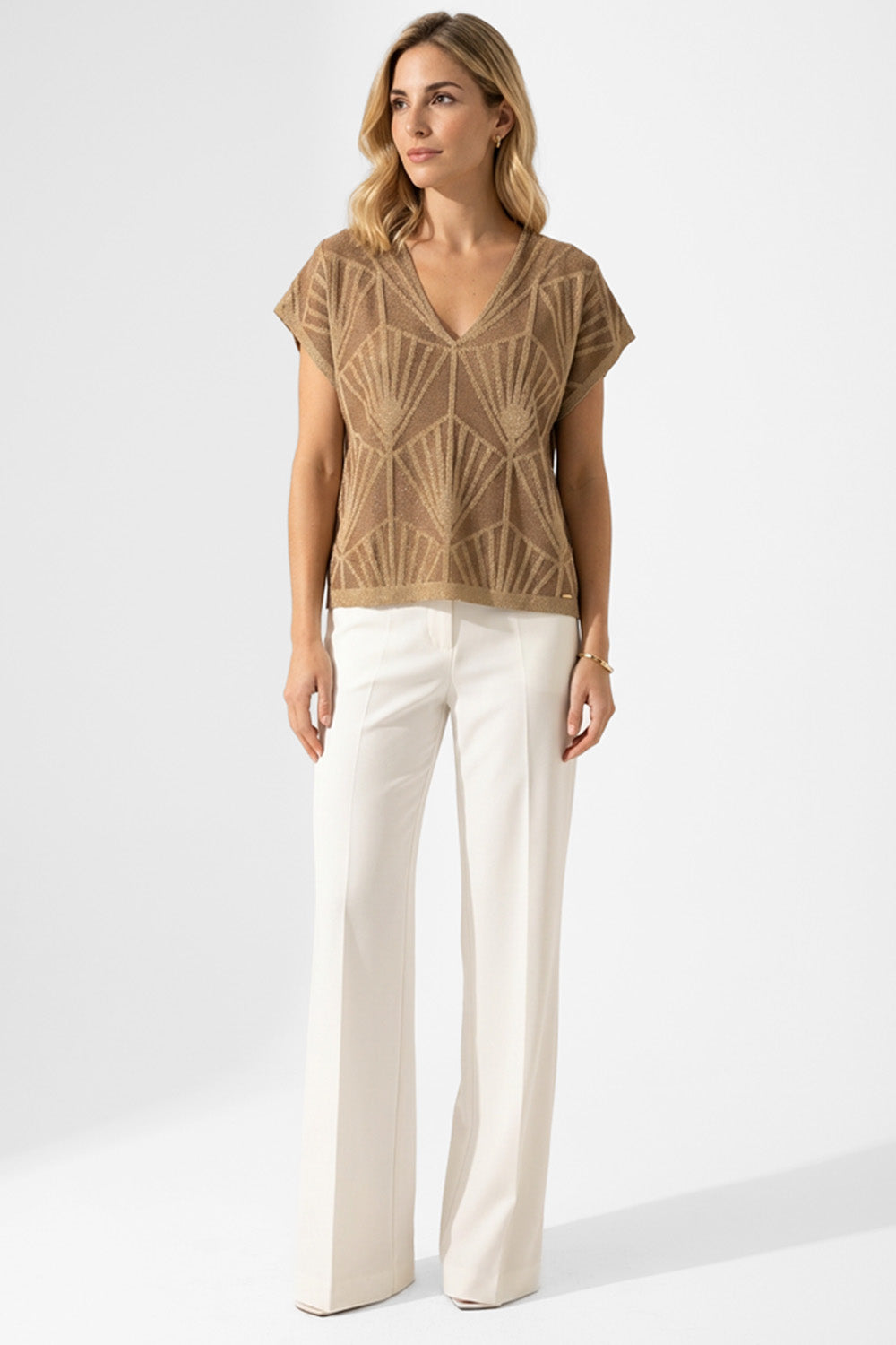 Woman wearing Πλεκτή Μπλούζα με Γεωμετρικό Σχέδιο σε Χρυσό Μπεζ and white trousers.