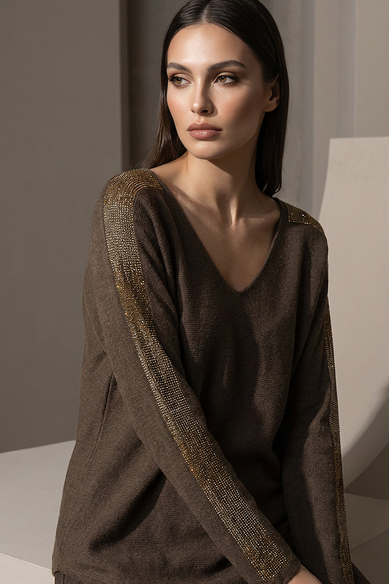 Καφέ πλεκτή μπλούζα με V λαιμόκοψη και χρυσές λεπτομέρειες σε ώμους και μανίκια, φορεμένη από μοντέλο studio.
