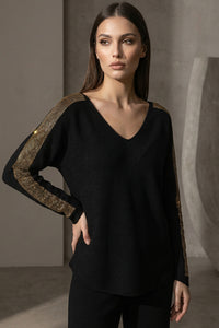 Μαύρη πλεκτή μπλούζα με V λαιμόκοψη και χρυσές λεπτομέρειες στους ώμους και μανίκια, φορεμένη από μοντέλο studio.