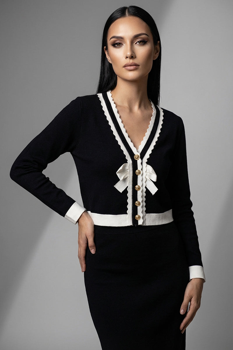 Μαύρη πλεκτή ζακέτα με λευκές λεπτομέρειες, χρυσά κουμπιά και διακοσμητικούς φιόγκους μπροστά.