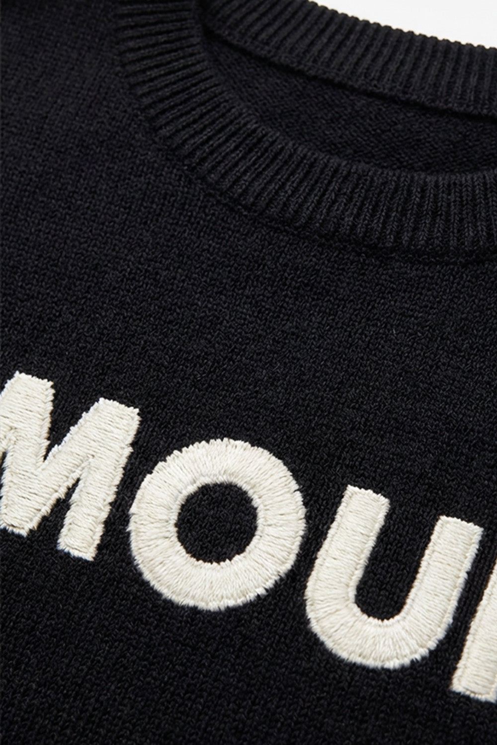 Μαύρη πλεκτή μπλούζα AMOUR με λευκό κεντημένο σχέδιο στο μπροστινό μέρος, φορεμένη από μοντέλο.