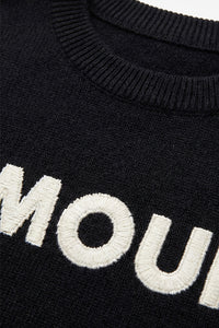 Μαύρη πλεκτή μπλούζα AMOUR με λευκό κεντημένο σχέδιο στο μπροστινό μέρος, φορεμένη από μοντέλο.