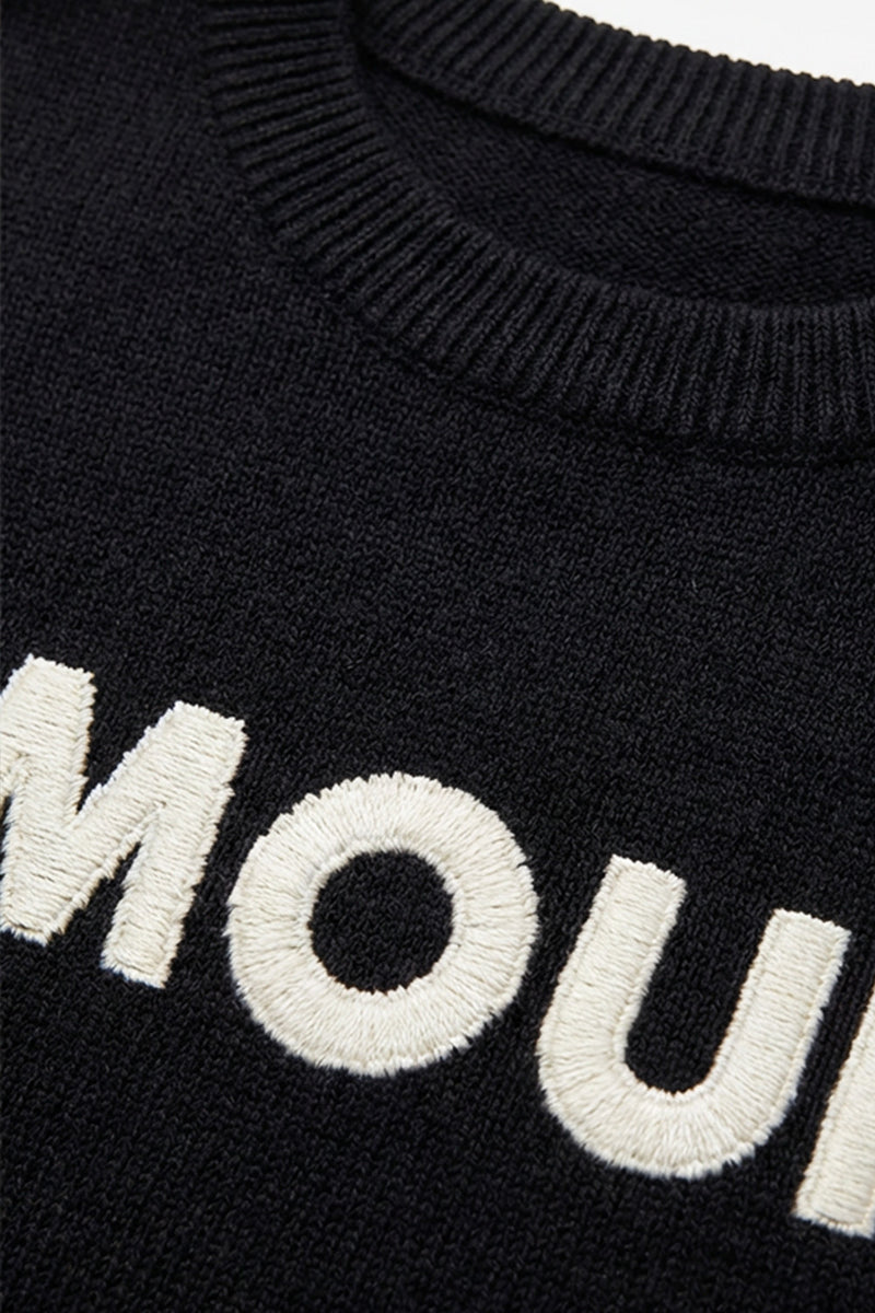 Μαύρη πλεκτή μπλούζα AMOUR με λευκό κεντημένο σχέδιο στο μπροστινό μέρος, φορεμένη από μοντέλο.