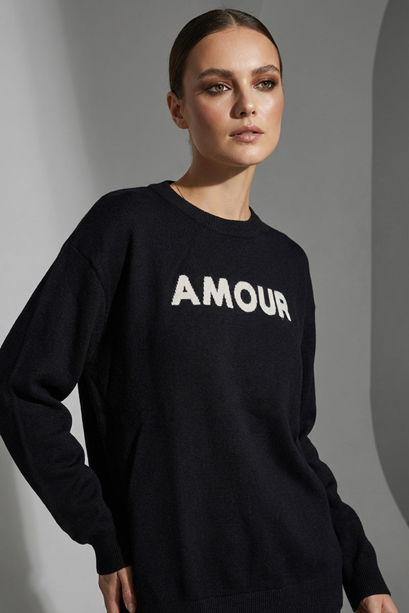 Μαύρη πλεκτή μπλούζα AMOUR με λευκό κεντημένο σχέδιο στο μπροστινό μέρος, φορεμένη από μοντέλο.