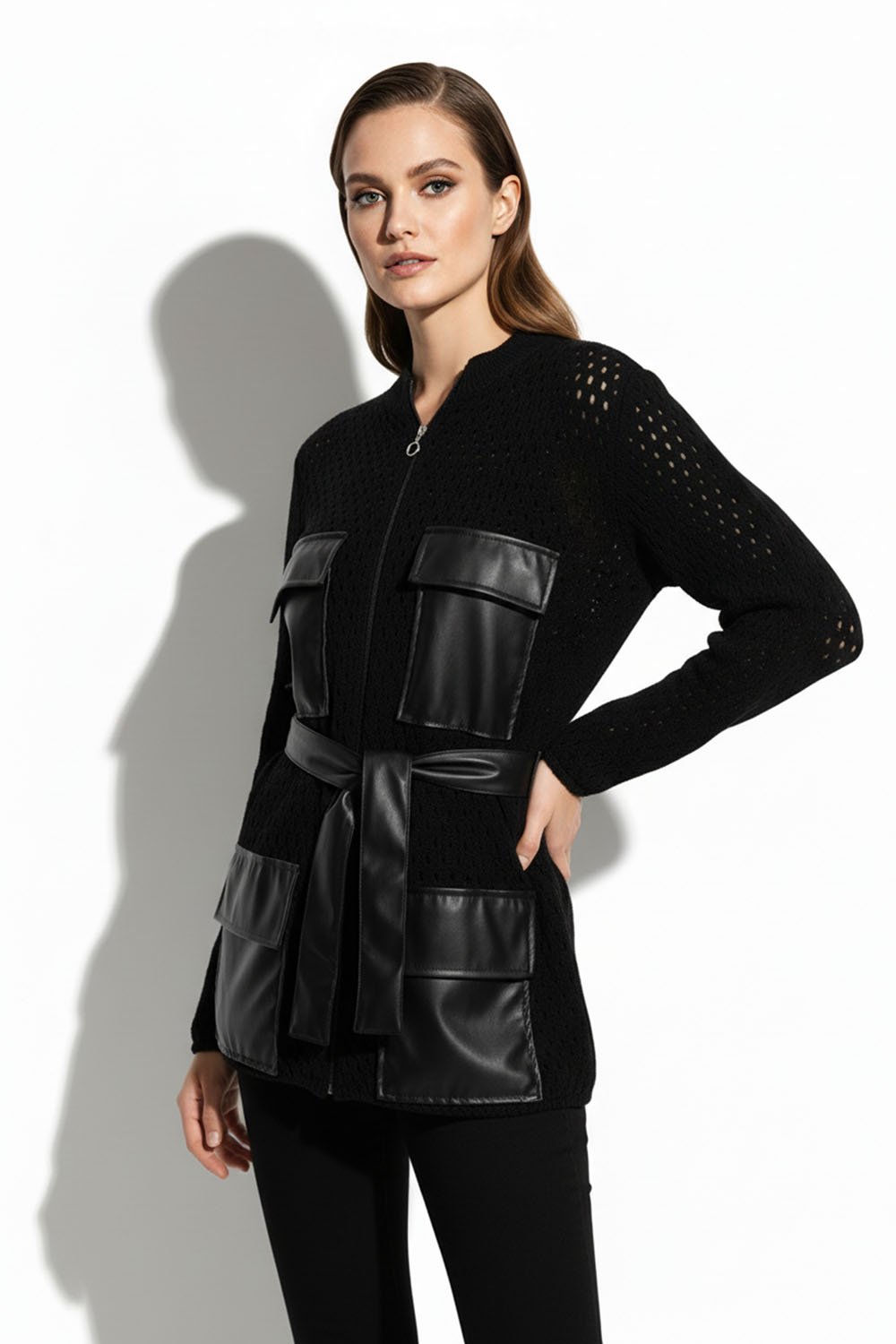 Μαύρη πλεκτή ζακέτα με τσέπες και ζώνη δερματίνης σε στούντιο φωτογράφισ
