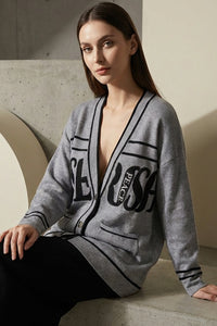 Πλεκτή γκρι ζακέτα με μαύρες λεπτομέρειες και lettering στο μπροστινό μέρος, φορεμένη από μοντέλο.