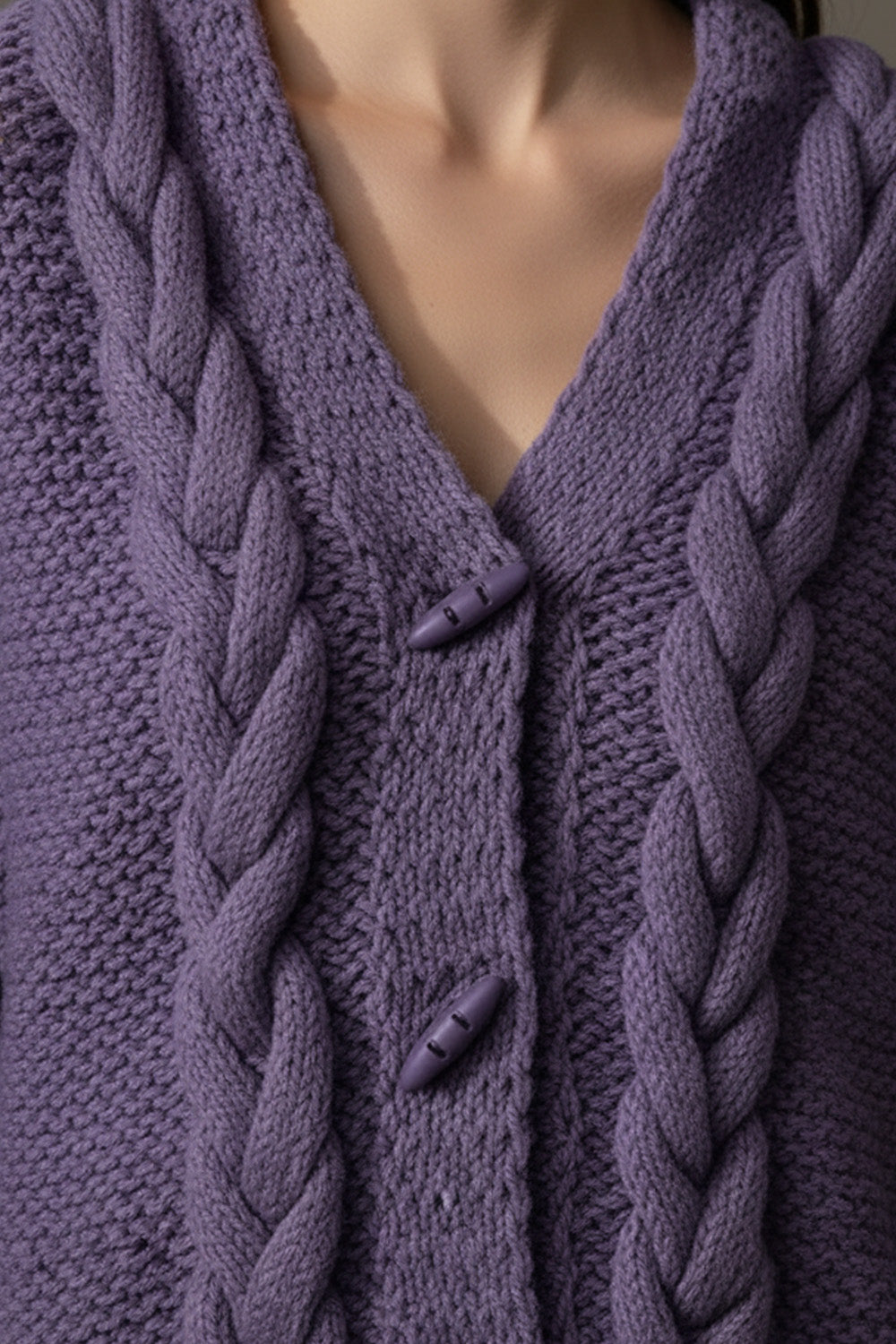 Πλεκτή γυναικεία ζακέτα με πλεξούδες και V ντεκολτέ σε μωβ απόχρωση, φορεμένη σε μοντέλο.