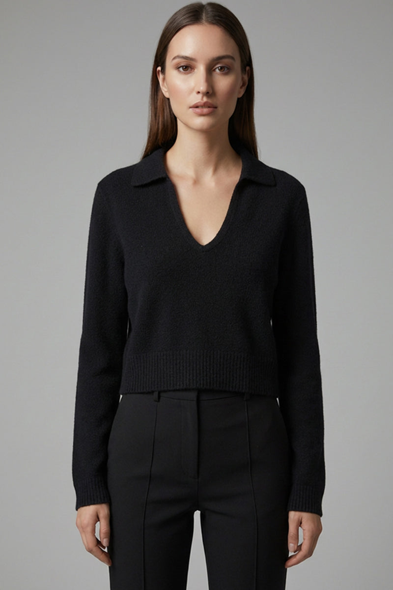 Μαύρη πλεκτή μπλούζα με γιακά, V λαιμόκοψη, μακρύ μανίκι και ριμπ τελείωμα, φορεμένη με μαύρο παντελόνι.