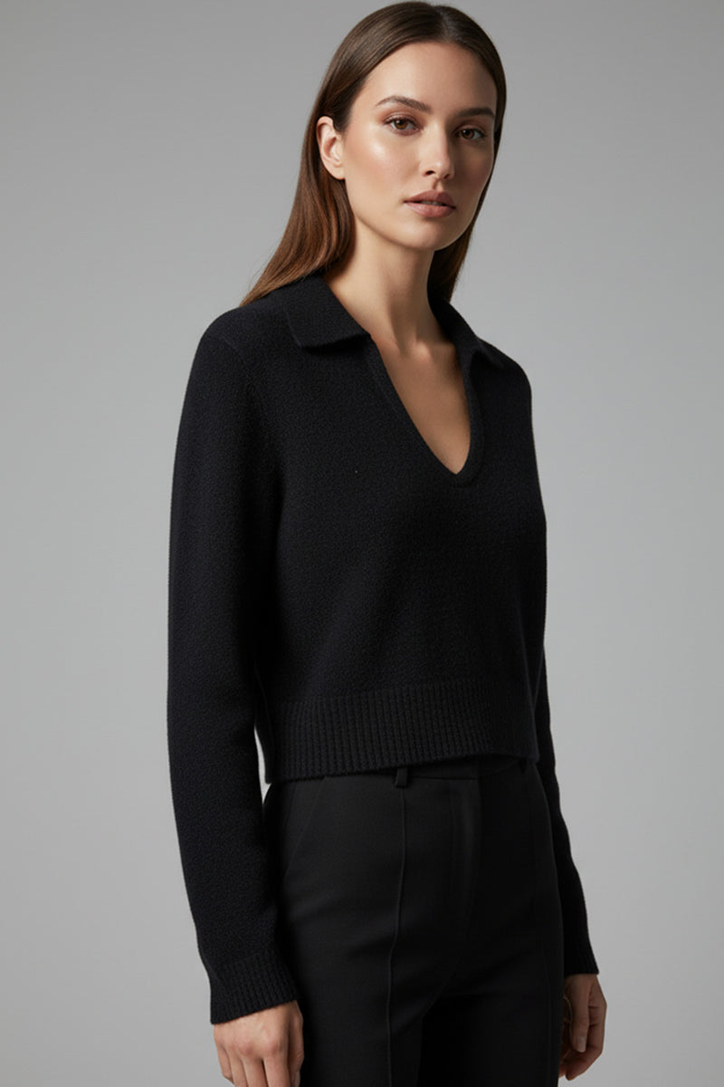 Μαύρη πλεκτή μπλούζα με γιακά, V λαιμόκοψη, μακρύ μανίκι και ριμπ τελείωμα, φορεμένη με μαύρο παντελόνι.