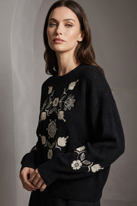 Μαύρο πλεκτό πουλόβερ με κεντημένο floral σχέδιο σε εκρού αποχρώσεις, φορεμένο από μοντέλο.