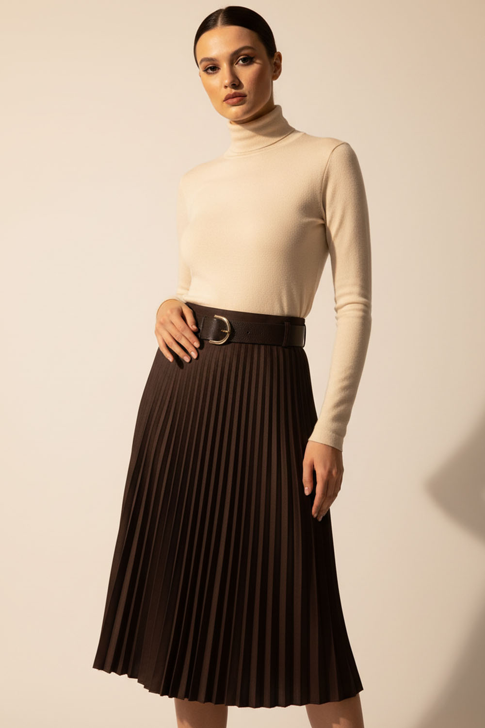 Καφέ πλισέ μίντι φούστα με ζώνη και αγκράφα σε στούντιο φωτογράφιση