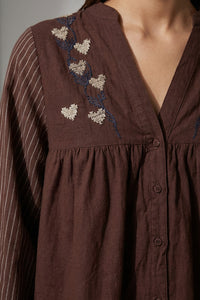 Καφέ γυναικείο πουκάμισο με κεντημένες καρδιές και ριγέ μανίκια σε χαλαρή γραμμή, φορεμένο από μοντέλο.