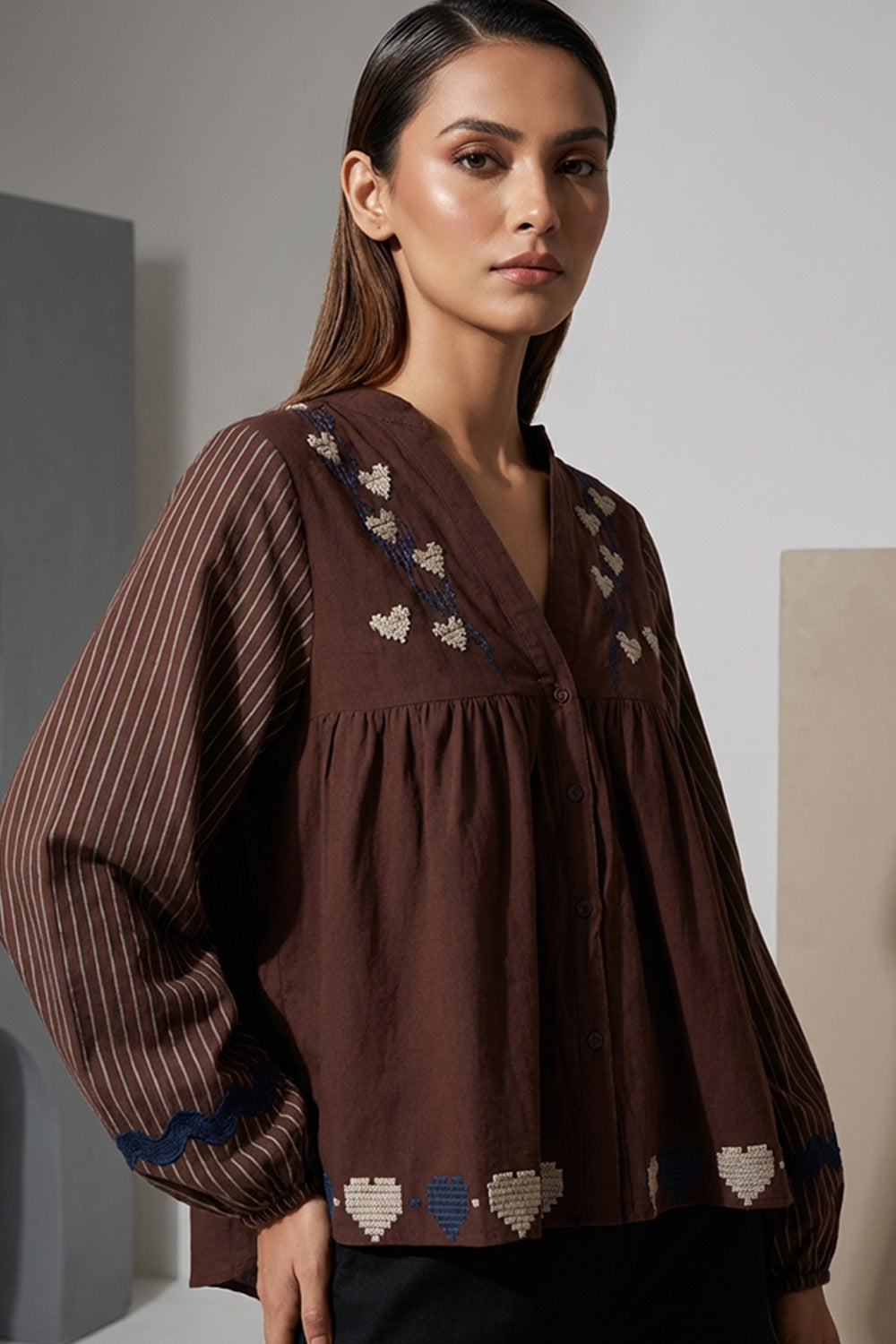 Καφέ γυναικείο πουκάμισο με κεντημένες καρδιές και ριγέ μανίκια σε χαλαρή γραμμή, φορεμένο από μοντέλο.