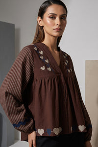 Καφέ γυναικείο πουκάμισο με κεντημένες καρδιές και ριγέ μανίκια σε χαλαρή γραμμή, φορεμένο από μοντέλο.