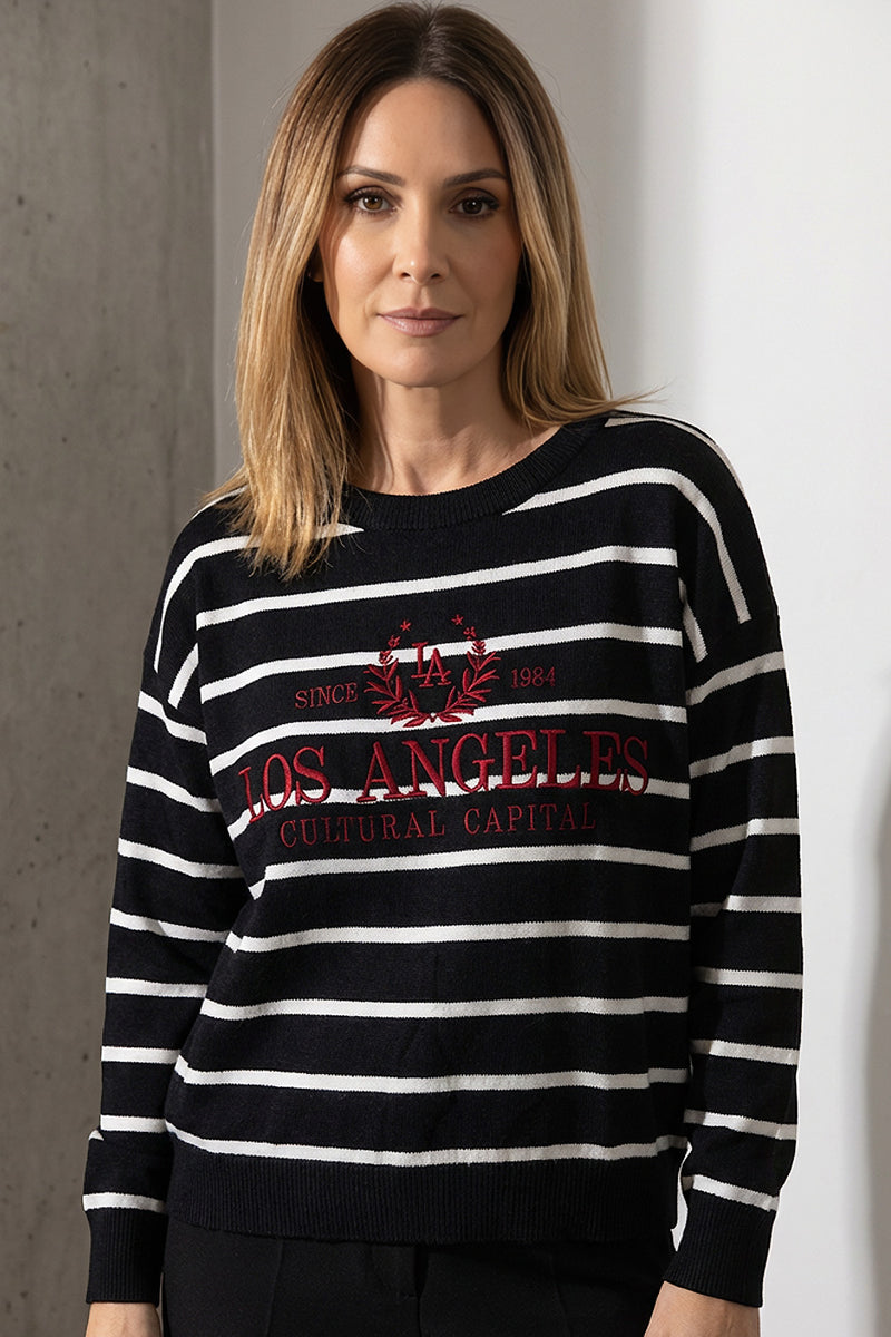 Γυναικείο μαύρο ριγέ πλεκτό με λευκές ρίγες και κεντημένο σχέδιο στο μπροστινό μέρος, φορεμένο από μοντέλο.