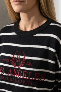 Γυναικείο μαύρο ριγέ πλεκτό με λευκές ρίγες και κεντημένο σχέδιο στο μπροστινό μέρος, φορεμένο από μοντέλο.