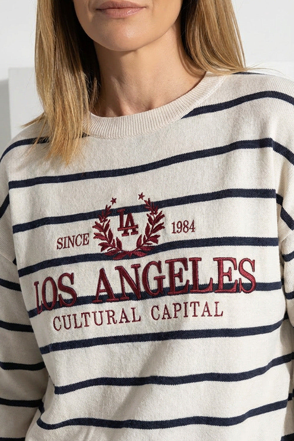 Γυναικείο ριγέ πλεκτό μπλουζάκι σε εκρού χρώμα με κεντημένο σχέδιο και μακριά μανίκια, φορεμένο από μοντέλο.