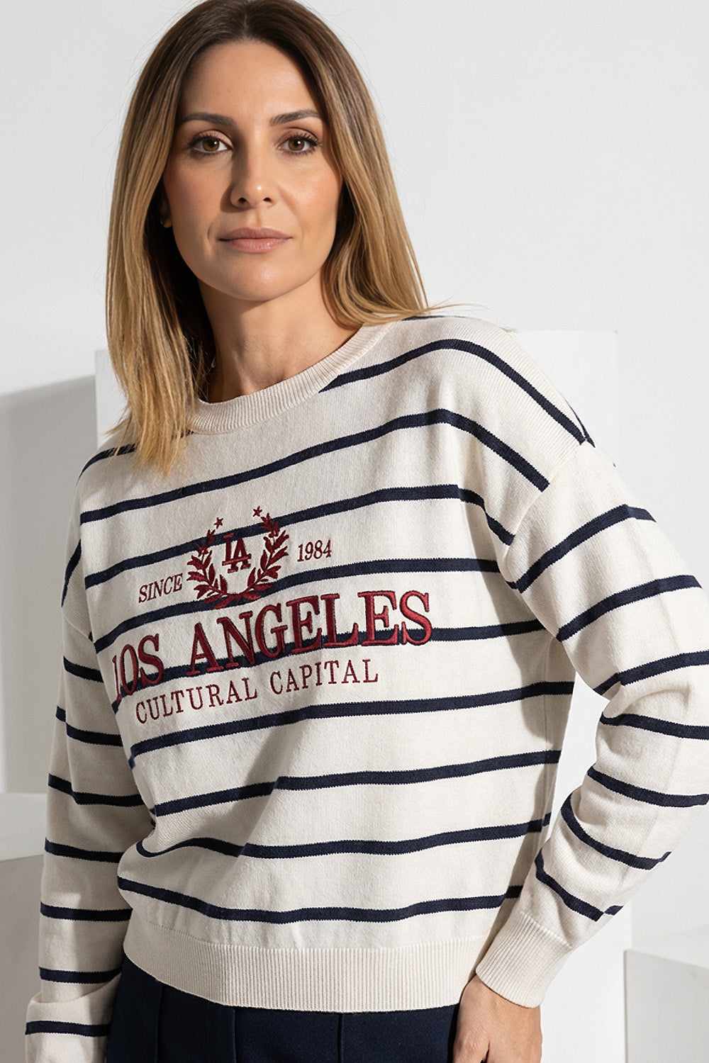 Γυναικείο ριγέ πλεκτό μπλουζάκι σε εκρού χρώμα με κεντημένο σχέδιο και μακριά μανίκια, φορεμένο από μοντέλο.