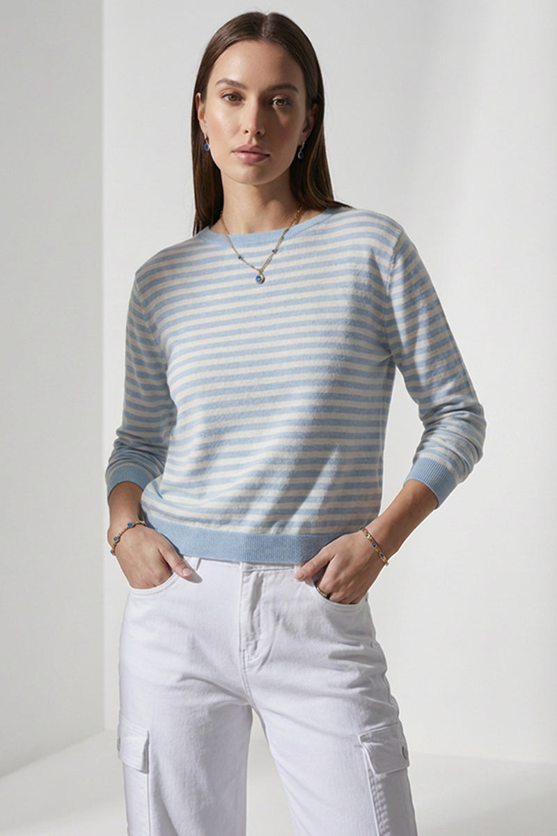 Γυναικείο ριγέ πλεκτό μπλουζάκι σε γαλάζιο και εκρού με μακρύ μανίκι και ελαστική πλέξη, φορεμένο με λευκό cargo παντελόνι.